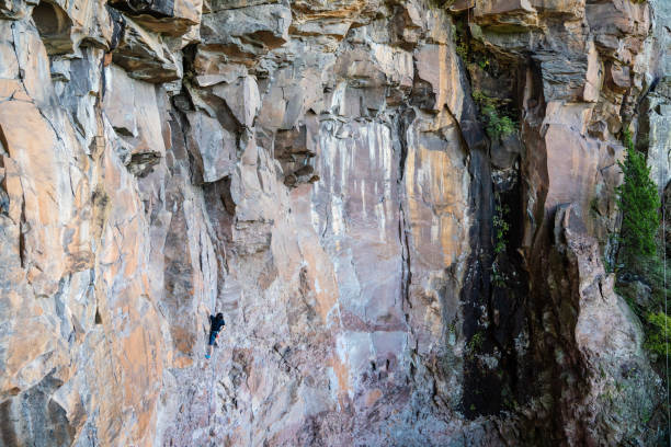 Young Japanese man rock climbing in an extreme location op a huge rock face
