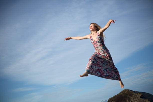 istock Clumpsy jump young positive woman blue sky 1069877992