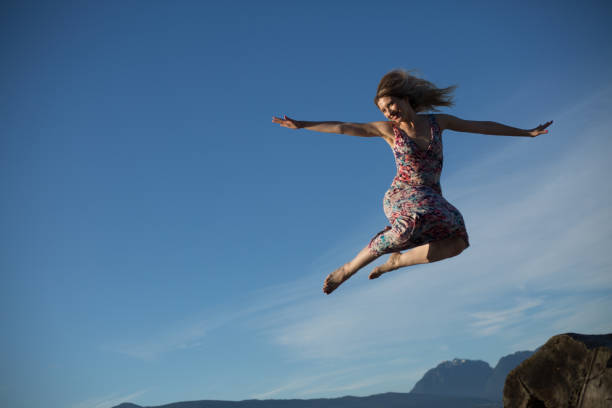 istock Joyful ninja like woman jumping blue sky 1069878104