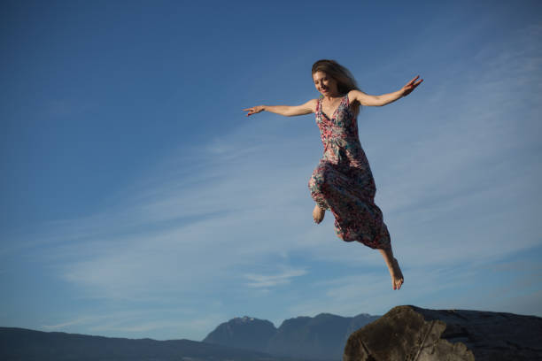 istock Smiling young female jumping in sky looking down 1069878126