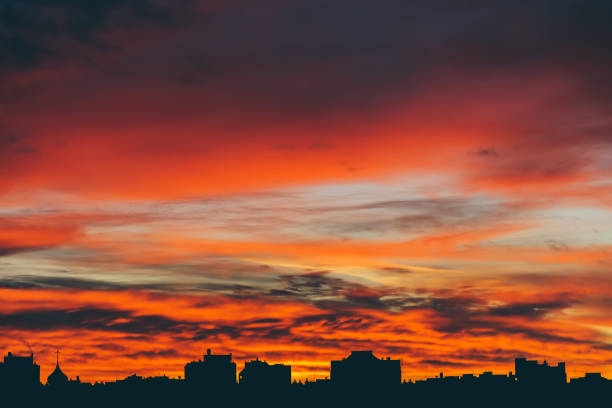 istock Cityscape with wonderful varicolored vivid dawn. Amazing dramatic multicolored cloudy sky above dark silhouettes of city buildings. Atmospheric background of sunrise in overcast weather. Copy space. 1069879528