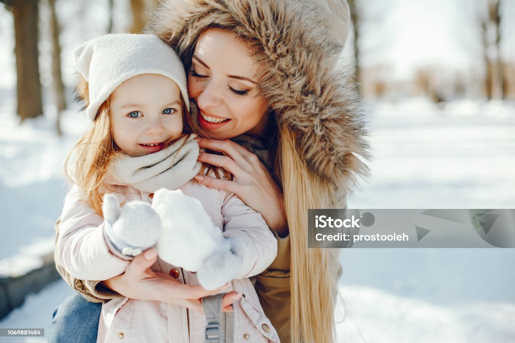 mother with daughter A young and stylish mom plays with her little beautiful daughter in a snowy snowy park Christmas Stock Photo