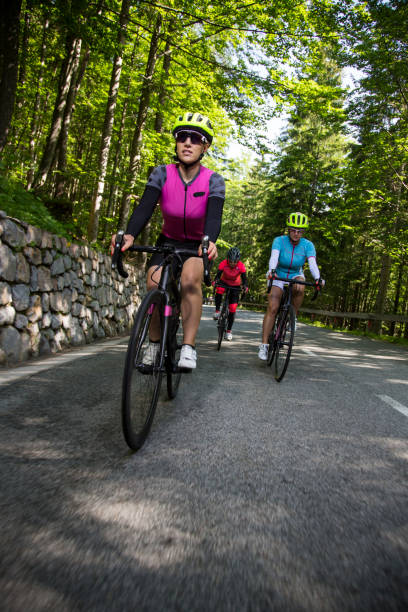 drei frauen reiten rennräder auf bergstraße - cyclist cycling road women stock-fotos und bilder