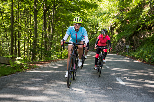 Three female riders riding road bikes on mountain road.