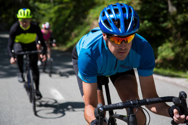 hombres y mujeres montar en bici de carretera en carretera de montaña - cycle racing fotografías e imágenes de stock