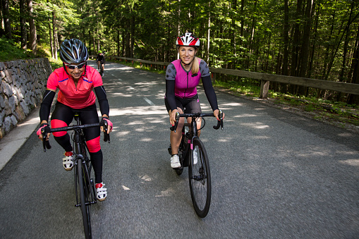 Two female riders riding road bikes on mountain road.