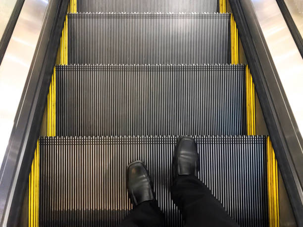 istock Businessman wore black leather shoes standing on the escalator. Down the elevator. 1069897946