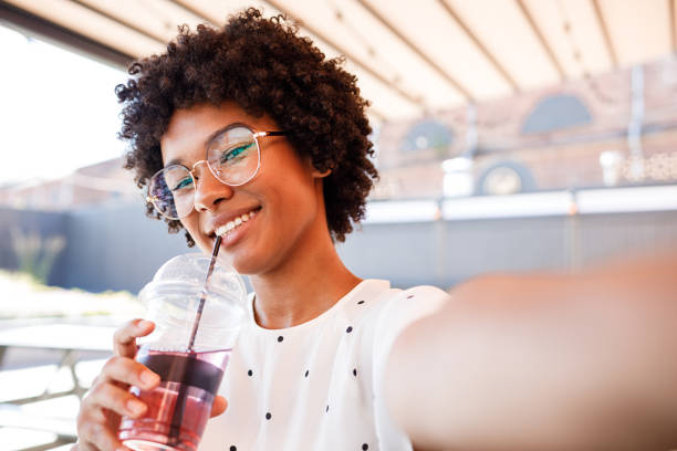 istock Smiling woman posing for a selfie with a drink in her hand 1069903766