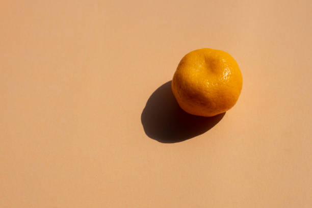 istock a whole oranges with strong shadow on orange background, copy space 1069907192