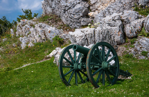 istock a gun standing next to a large stone on a green hill 1069911262