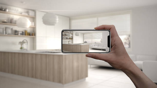 istock Hand holding smart phone, AR application, simulate furniture and interior design products in real home, architect designer concept, blur background, kitchen with shelves and cabinets 1069912962