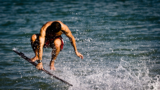 SINGAPORE - MAY 2011: An unidentified man does tricks on his surf board on Singapore sea. Extreme sport image of a surfer. Summer image of a person on recreational activity.