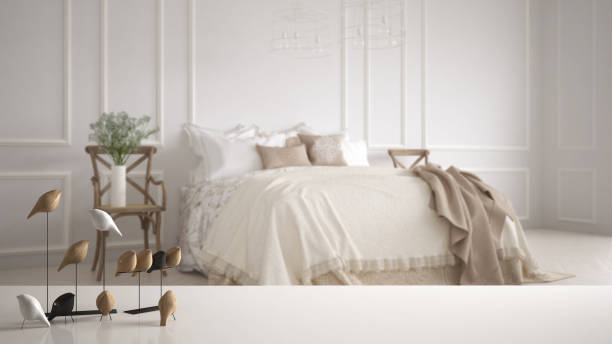 istock White table top or shelf with minimalistic bird ornament, birdie knick - knack over blurred vintage bedroom with soft bed full of pillows and blankets, classic interior design 1069913678