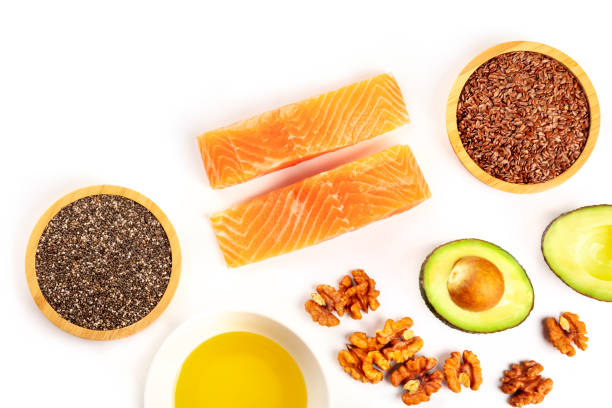 an overhead photo of healthy omega-3 diet food. raw salmon, avocado, nuts, chia seeds, and flaxseeds, shot from above on a white background with copy space - nutritional supplement salmon food flax imagens e fotografias de stock