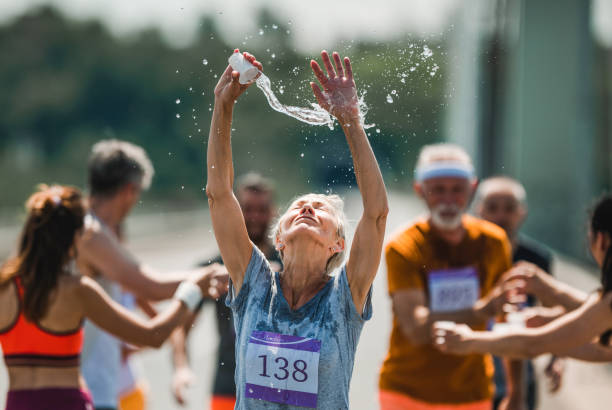 istock Senior marathon runner refreshing herself with water during a race. 1069919514