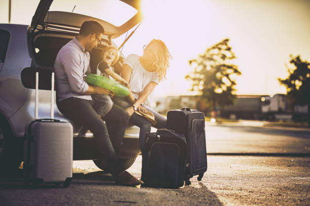 Young happy family talking before a trip by car.