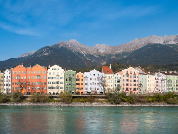 maisons colorées de la rivière inn, avec les montagnes en arrière-plan à mariahilfstrasse à innsbruck, autriche - mariahilfstrasse photos et images de collection