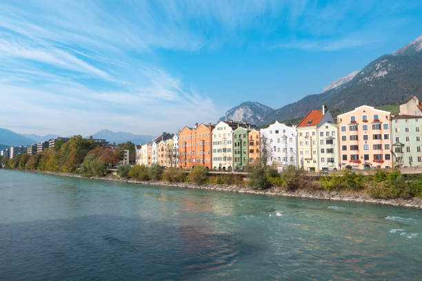 maisons colorées de la rivière inn, avec les montagnes en arrière-plan à mariahilfstrasse à innsbruck, autriche - mariahilfstrasse photos et images de collection