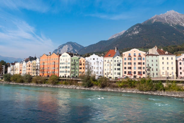 maisons colorées de la rivière inn, avec les montagnes en arrière-plan à mariahilfstrasse à innsbruck, autriche - mariahilfstrasse photos et images de collection