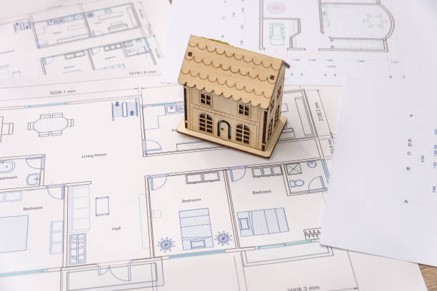 istock Wooden house model with blueprint and laptop 1069928110