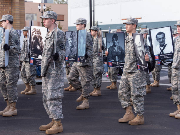 Veterans Day Parade Albany Oregon Junior ROTC Honoring WWII Generation Albany, Oregon, USA - November 10, 2018 : This part of the parade in downtown Albany shows Lebanon Junior ROTC members marching. They are holding pictures to honor the legacy of the WWII generation. This large Veteran's Day Parade is held annually in Albany, Oregon. military parade stock pictures, royalty-free photos & images