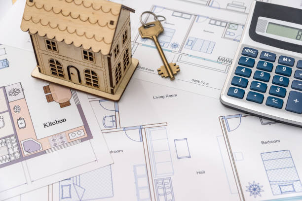istock Wooden house model and key on house plan drawing 1069931036