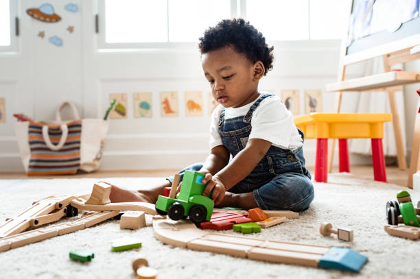 bambino carino che gioca con un giocattolo del treno ferroviario - child preschool toy playing foto e immagini stock