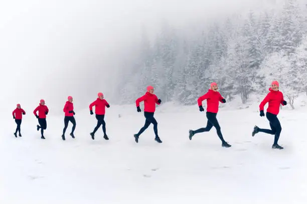 Girls running together on snow in winter mountains. Sport, fitness inspiration and motivation. Happy group of women trail running in mountains, winter day. Multiple female trail runners on snow