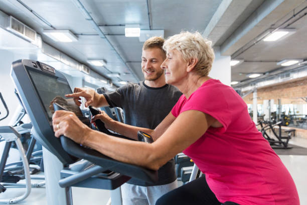 ältere frau, die rehabilitation in turnhalle - spinning instructor exercising gym stock-fotos und bilder