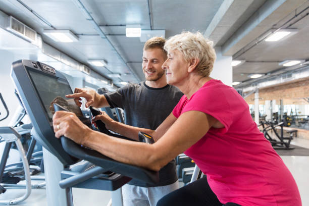 elderly woman having rehabilitation in gym - spinning instructor exercising gym imagens e fotografias de stock