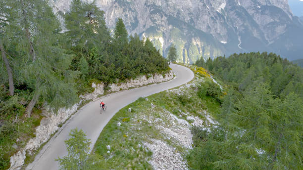 istock Road cyclist riding on beautiful mountain road surrounded by forest 1069941368