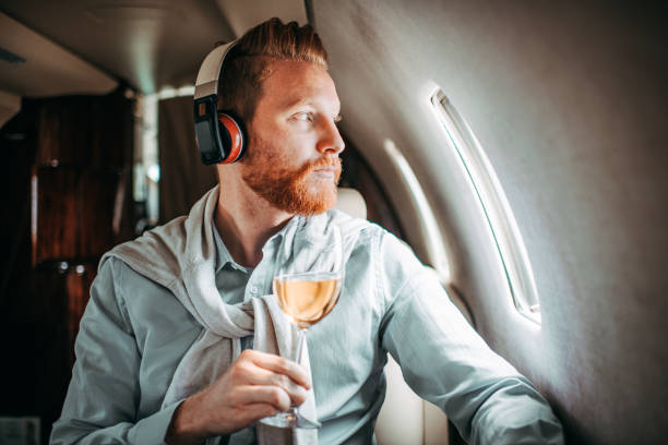 młody biznesmen pijący wino na prywatnym odrzutowcu - upper class audio zdjęcia i obrazy z banku zdjęć