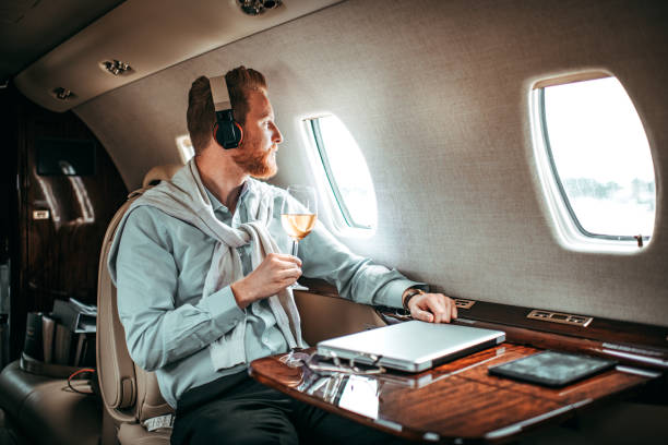 jeune homme d’affaires, boire du vin sur un jet privé - status symbol audio photos et images de collection