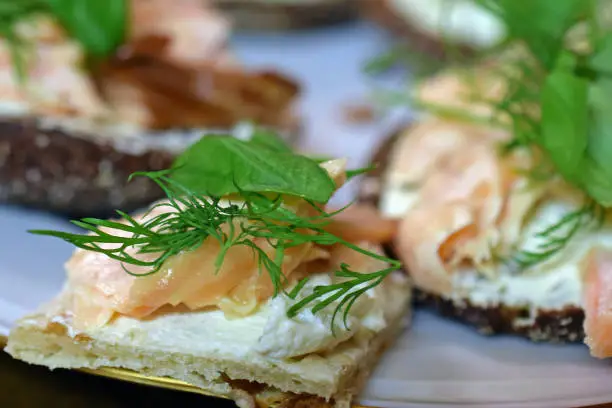 Canapés with smoked salmon, cream cheese, dill and basilica toppings. Horizontal image.