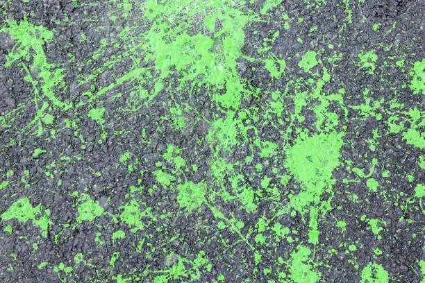Abstract art background. Green spots of paint on asphalt