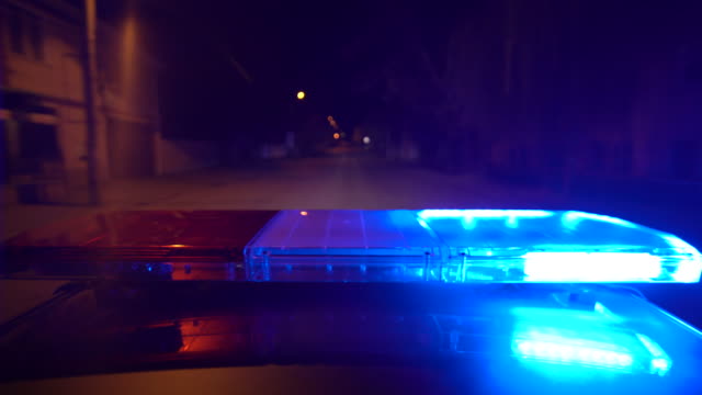 Driving police car with blue red emergency lights flashing at night