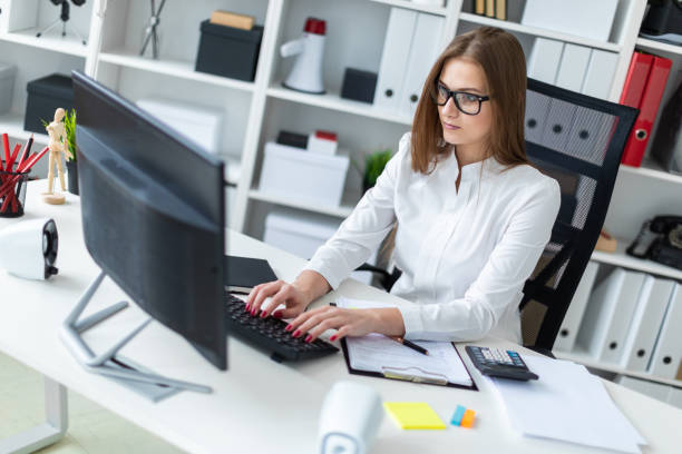 istock Young girl sitting at the table and working with a computer, documents and calculator 1069952564