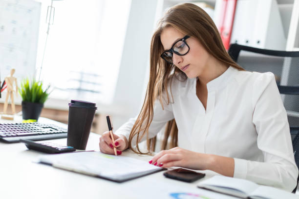 istock Young girl sitting at the table and working with a computer, documents and calculator 1069952648