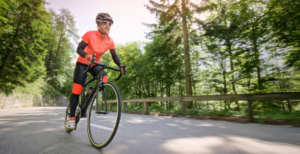 frau reiten rennrad auf bergstraße - cyclist cycling road women stock-fotos und bilder