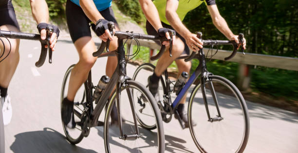 Three men riding road bikes on mountain road Low section of three male riders riding road bikes on mountain road. cycle racing stock pictures, royalty-free photos & images