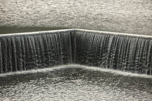 Small dam with water flowing rapids. Seen as lines and patterns with foam