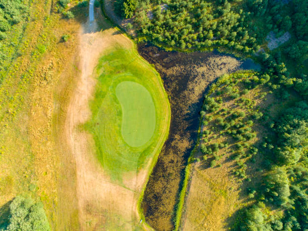 golf green surrounded by water traps and forest - sports flag high angle view putting sand imagens e fotografias de stock