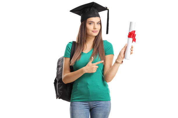 Female student with a graduation cap holding a diploma and pointing isolated on white background