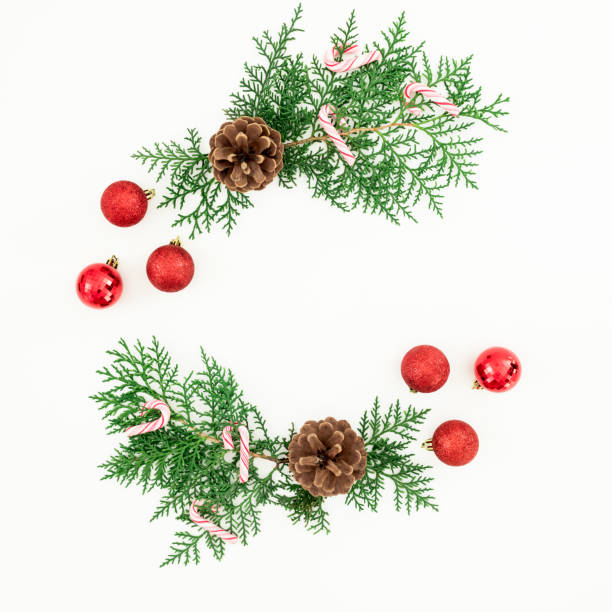 istock Christmas frame made of pine branches and red balls decoration with candy cane on white background. Flat lay, top view 1069971990