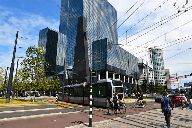 Tramways passing and pedestrians crossing the road in front of the Delft Gate Building,which is a twin-tower skyscraper complex, located nearby the Central railway station of Rotterdam,and was constructed between 1988 and 1991.