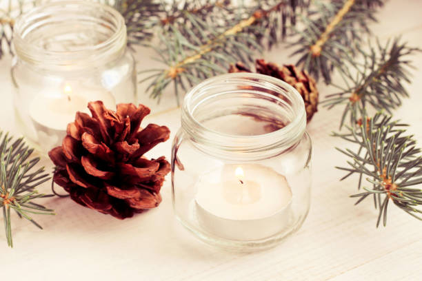 istock Candle in glass jar festive setting with fir tree twigs and pine cones. 1069979092