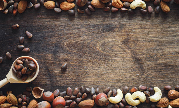 istock Different nuts on a wooden table. Cedar, cashew, hazelnut, walnuts and a spoon on the table. Many nuts are inshell and chistchenyh on a wooden background. 1069979448