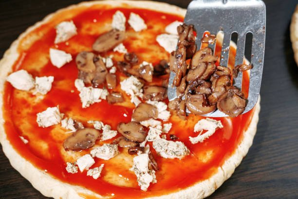 cogumelos para pizza, escápula para comida, cozinhar, carne de chiken, massa grossa, massa de pizza chef prepara deliciosa pizza em casa, pizza com frango e cogumelos, processo de cozimento, champignon - pizza sauces chef making - fotografias e filmes do acervo