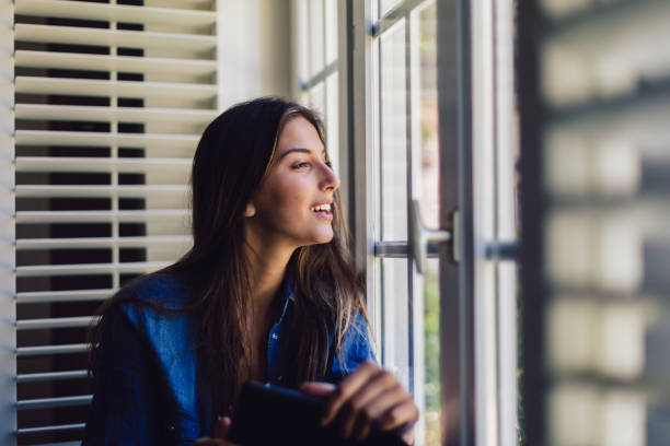 istock Woman at home reading book and staring through the window 1069982618