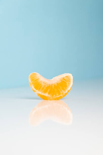 istock Wedge of tangerine on white and blue background. 1069985012